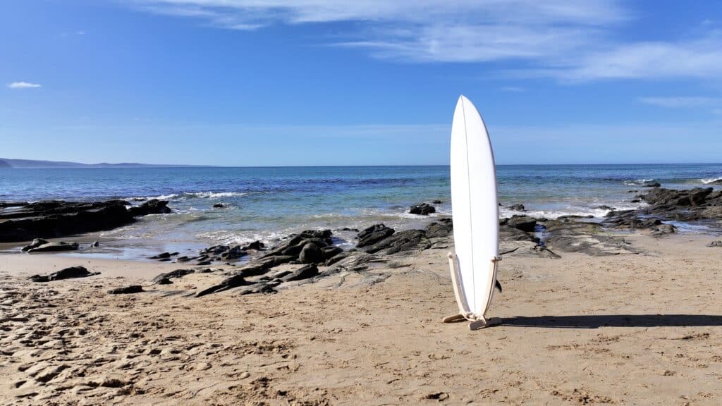 GLYD O Surfboard Standing Rack with surfboard mounted standing on Lorne Point beach. Rocks, Ocean and Sky in background.