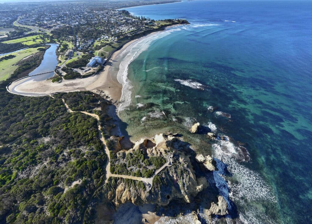 Aerial view of Torquay Point, Torquay Beach, and Point Danger along the southern coast of Victoria, Australia, with clear turquoise water, rocky cliffs, and coastal vegetation.