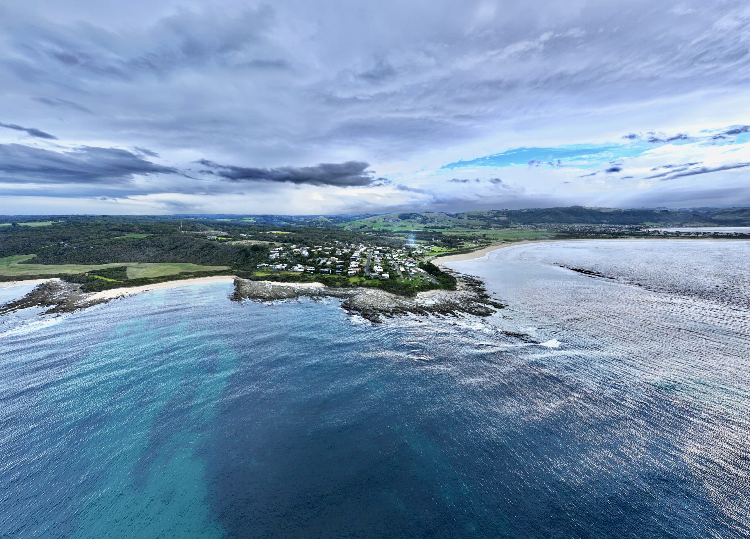 Aerial panorama of Marengo Point from high above Southern Ocean showing township and Great Ocean Road coastline.
